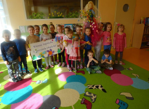 Grupa dzieci prezentuje plakat, panią Wiosnę i kukłę Marzanny.